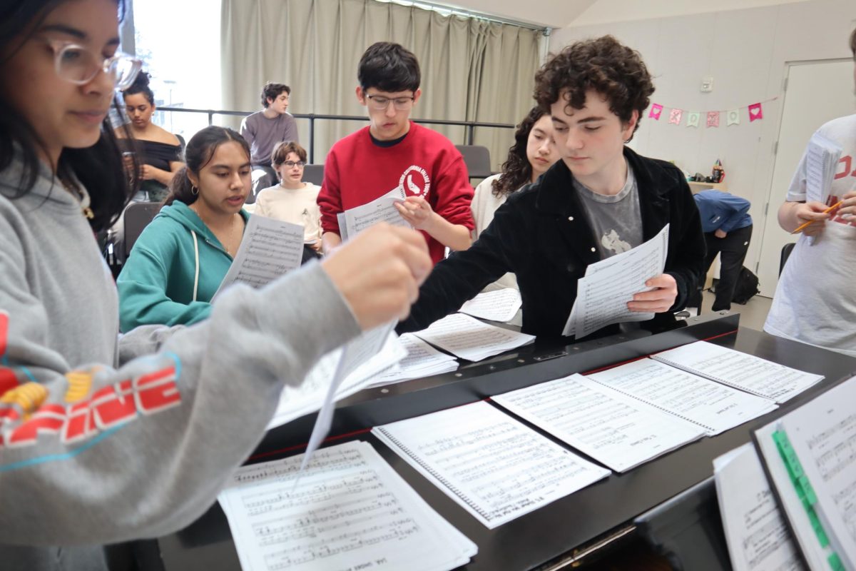 Cade Carcione '27 picks up sheet music at rehearsal.